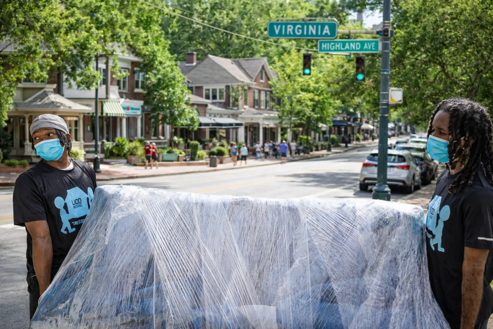 LIOO Moving movers carrying a wrapped couch in Virginia Highland, Atlanta, GA during a residential move.