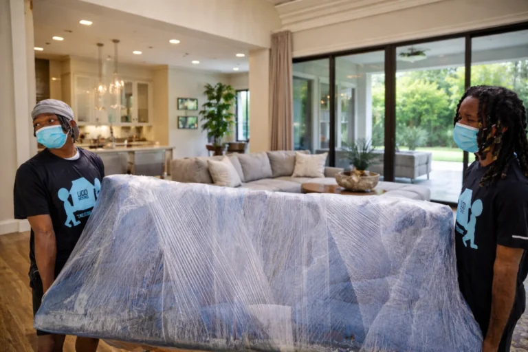 Professional residential movers from LIOO Moving carrying wrapped couch inside modern Atlanta home during local household move