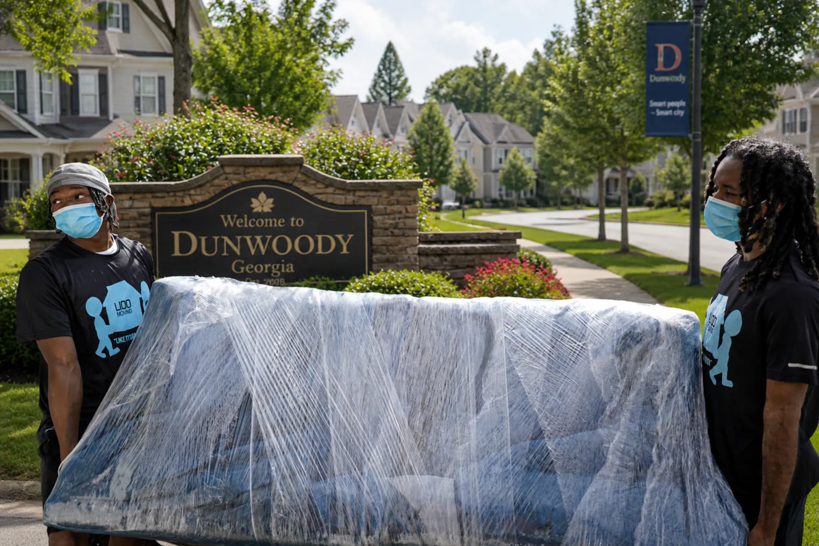 Professional movers in Dunwoody GA wrapping and carrying a couch for safe residential relocation
