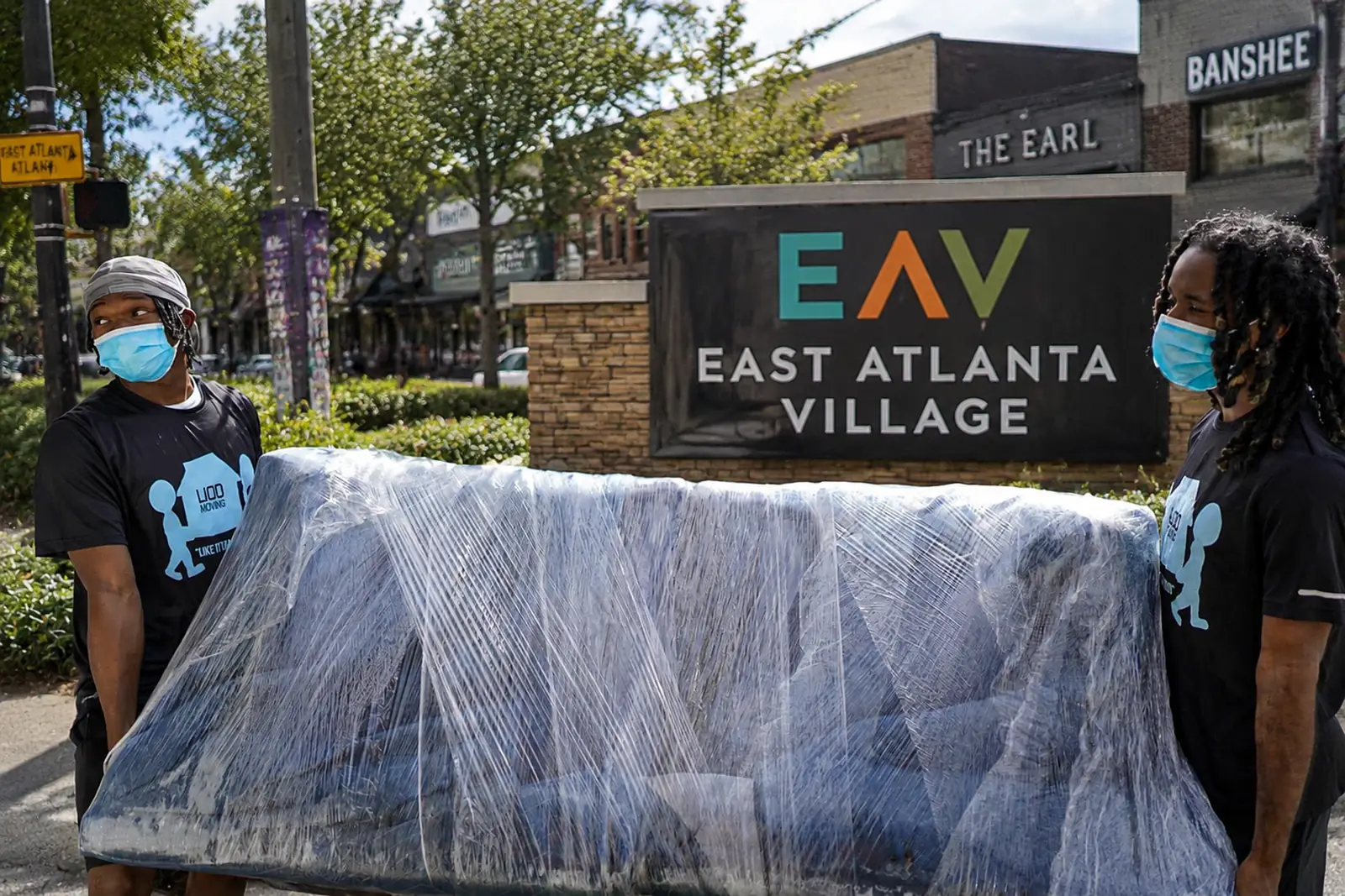 LIOO Moving crew carrying a wrapped couch through East Atlanta Village in Atlanta, Georgia