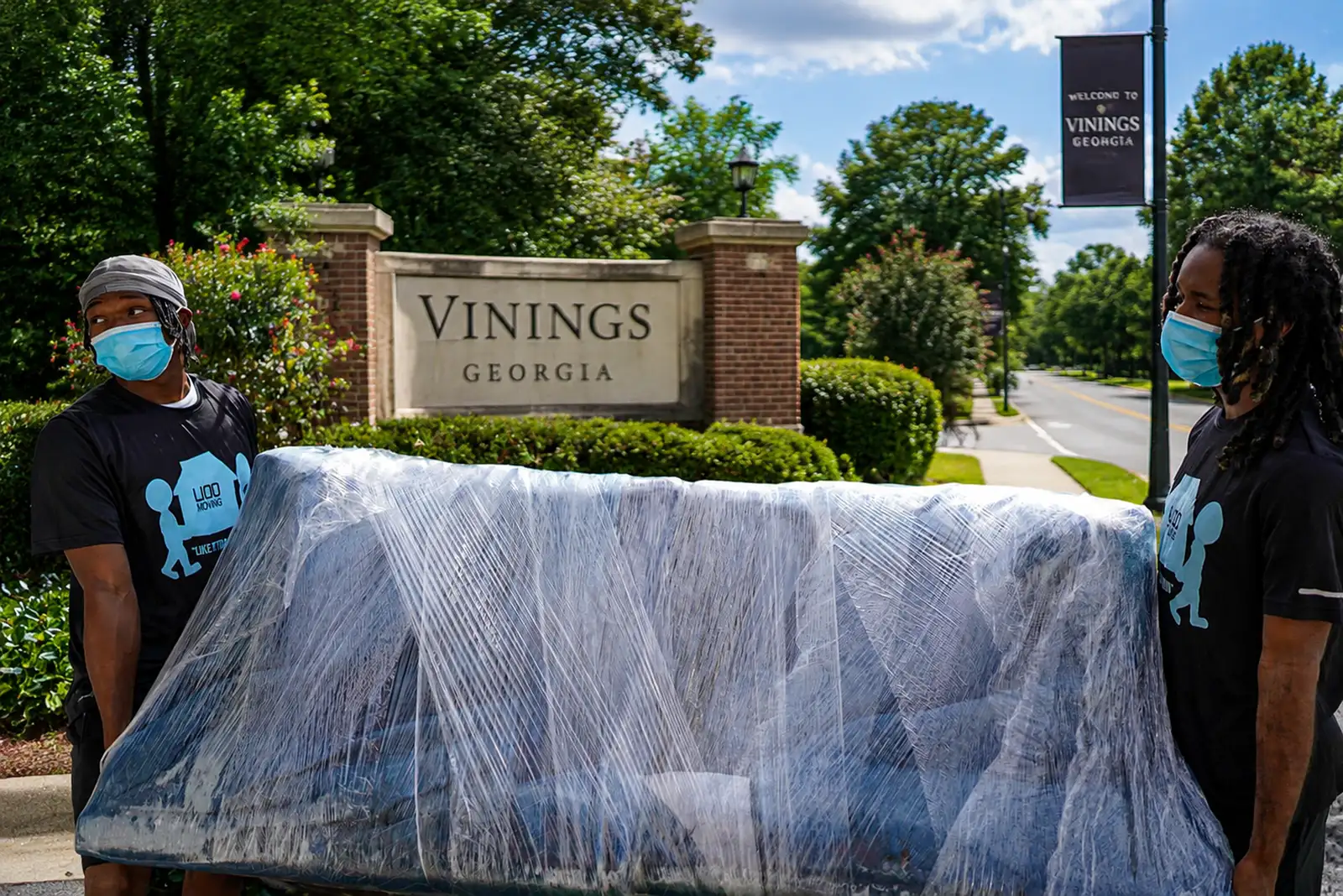 LIOO Moving crew carrying a wrapped couch through a residential neighborhood in Vinings, Georgia