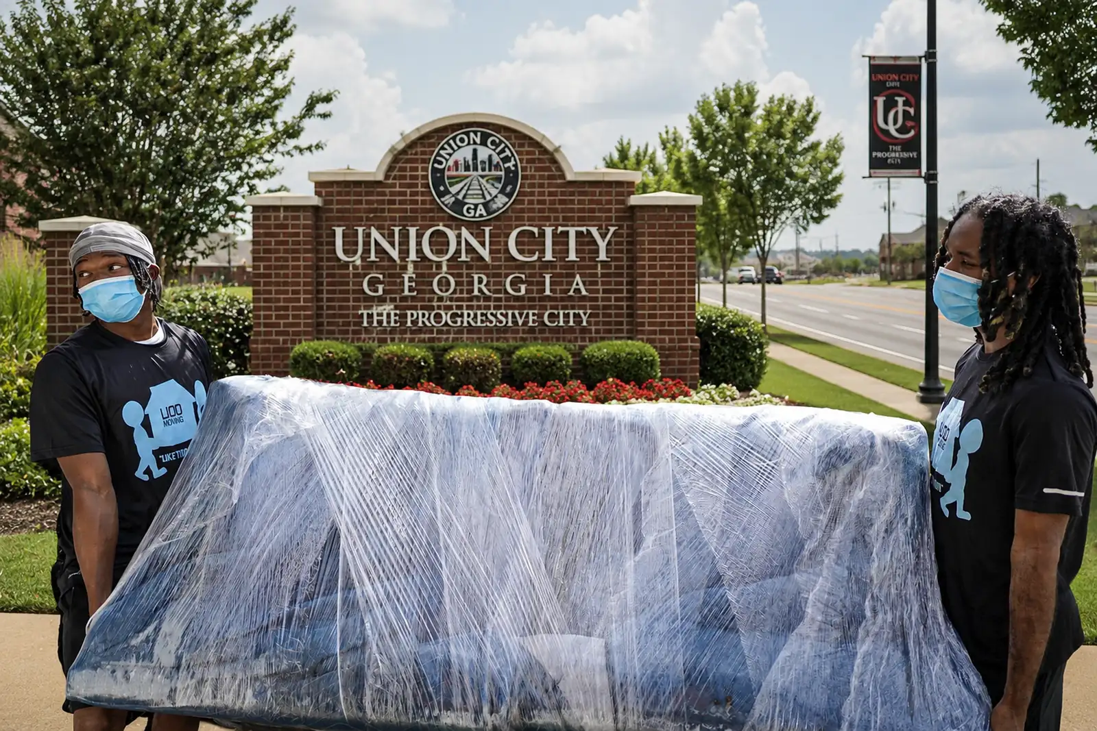 Professional Union City, GA movers carrying a furniture-wrapped sofa during a residential move in a neighborhood