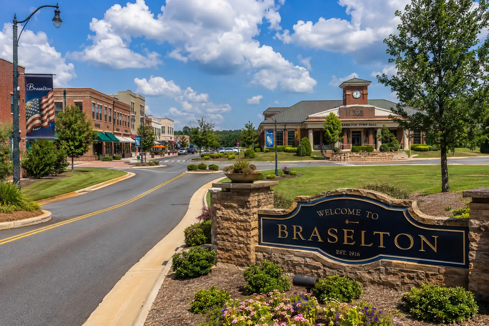Braselton welcome sign overlooks a landscaped downtown street with brick buildings and a civic clock tower