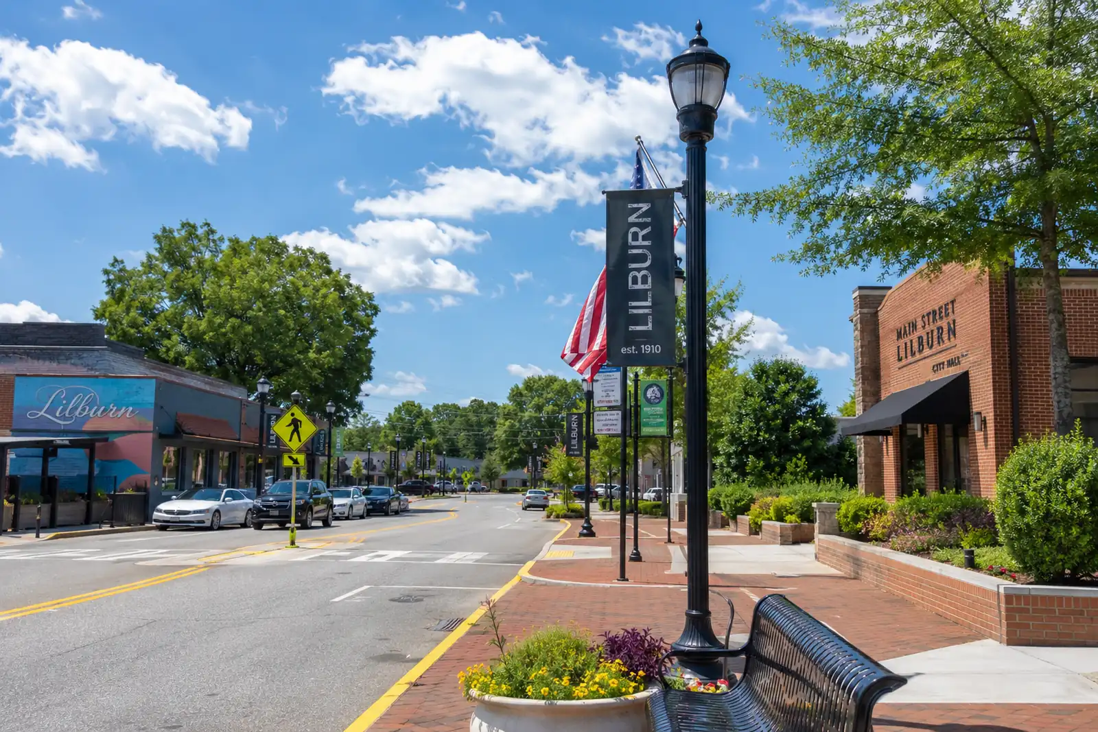 Downtown Lilburn street with brick sidewalks, storefronts, parked cars, and a prominent LILBURN banner